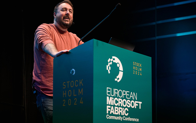 speaker standing behind a lectern addressing a room during a conference session