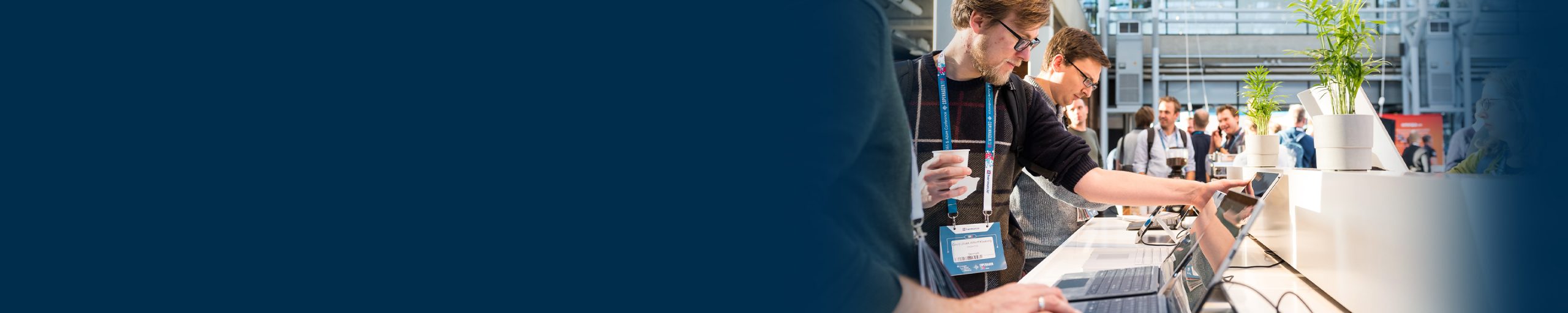 People working on laptops while standing at a table in the conference EXPO hall