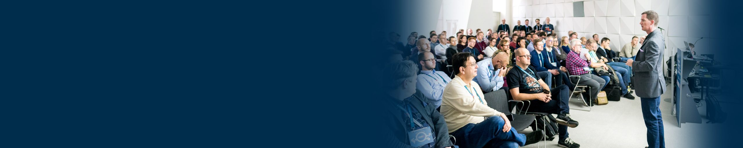 Man standing in front of a packed room as part of a session talk