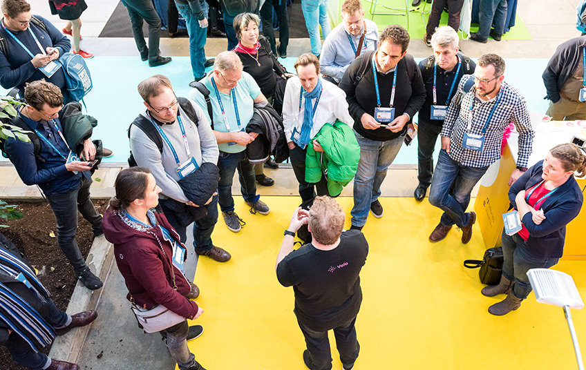 overhead shot of an expo booth where people are gathered around a person doing a demo