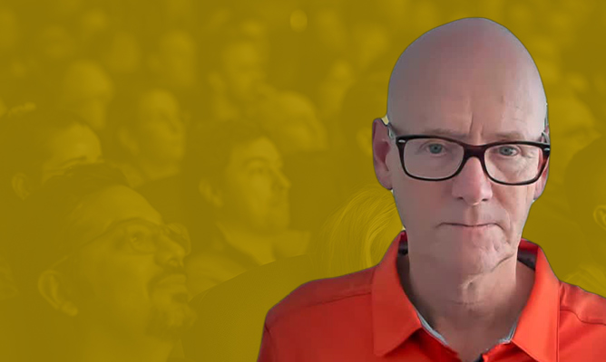 FabCon sponsor Arcene Goossens smiles for the camera over a background of a sitting audience